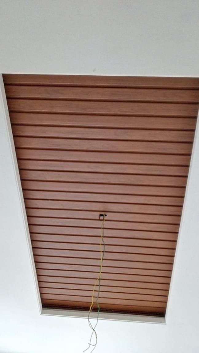 a room with a ceiling fan and wooden slats on the ceiling, along with a window