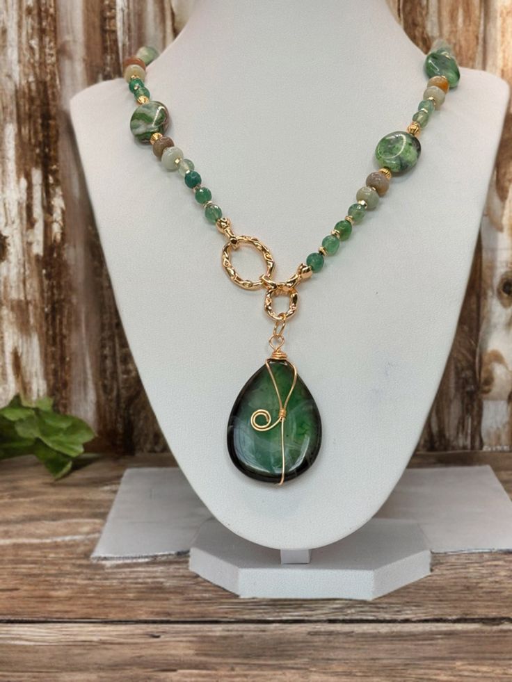 This exquisite piece is meticulously crafted with a stunning selection of green crazy lace agate and crackle agate beads, each chosen for its unique beauty and mesmerizing patterns. The focal point is a boldly polished crackle agate pendant, wrapped delicately in a golden wire spiral that adds a whimsical touch to its natural elegance. *Features: - Genuine Crazy Lace Agate Beads: Known for their intricate, swirling patterns, these beads are a symbol of joy and happiness. -Crackle Agate Pendant: Bohemian Green Onyx Necklaces With Natural Stones, Bohemian Green Onyx Necklace With Natural Stones, Handmade Elegant Malachite Beaded Necklaces, Handmade Elegant Aventurine Beaded Necklace, Elegant Handmade Aventurine Necklaces, Bohemian Green Onyx Beaded Necklace With Natural Stones, Bohemian Beaded Necklace With Green Onyx, Green Agate Stone Jewelry, Bohemian Green Agate Necklaces