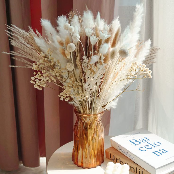 a vase filled with white flowers sitting on top of a table next to a book