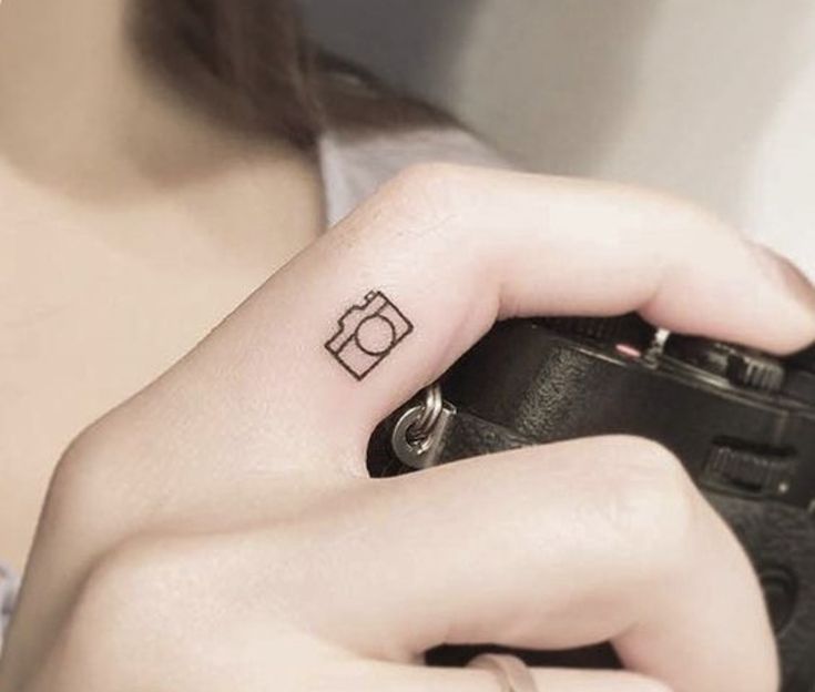 a woman with a camera tattoo on her left hand