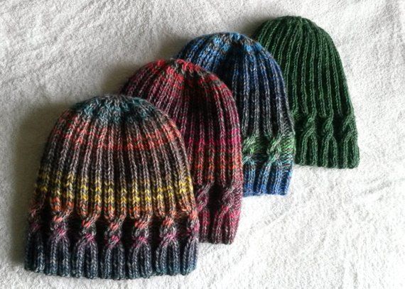 three knitted hats laying on top of a bed