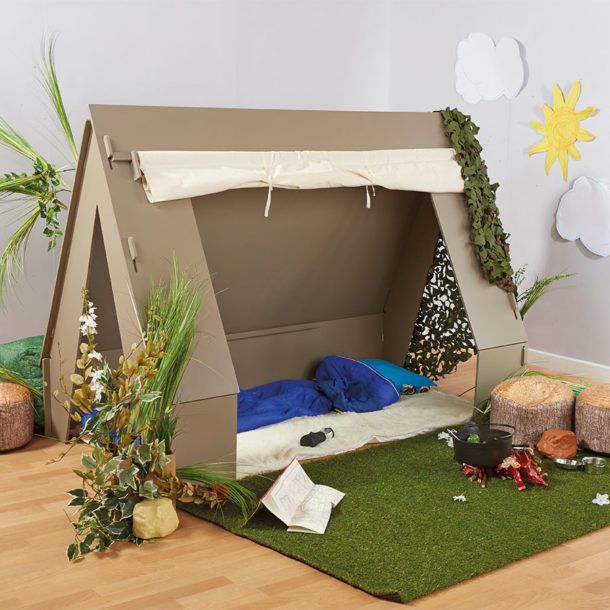 a child's play tent made out of cardboard with plants and rocks on the floor