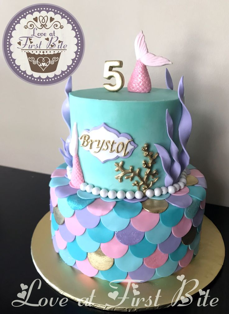 a blue and pink birthday cake with a little mermaid on top