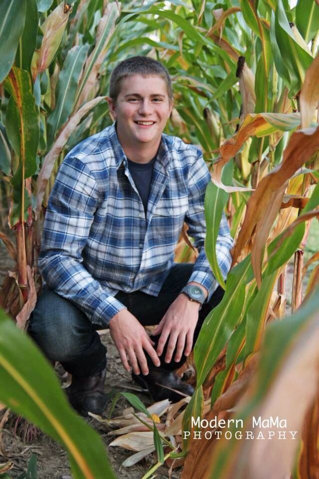 a man kneeling down in the middle of a corn field