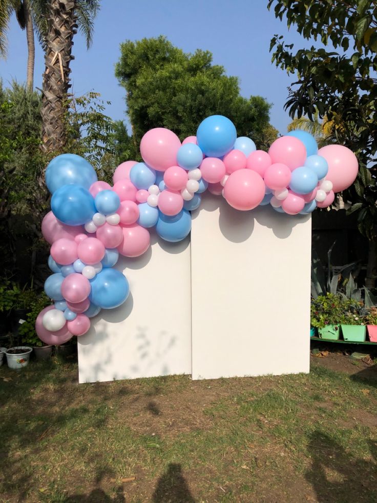 a bunch of balloons that are on the side of a wall in front of some trees