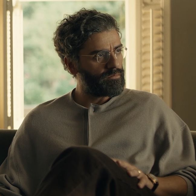 a bearded man with glasses sitting on a couch