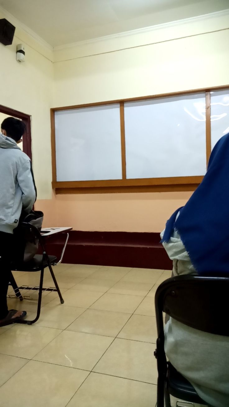 two men are sitting in chairs and one is looking out the window