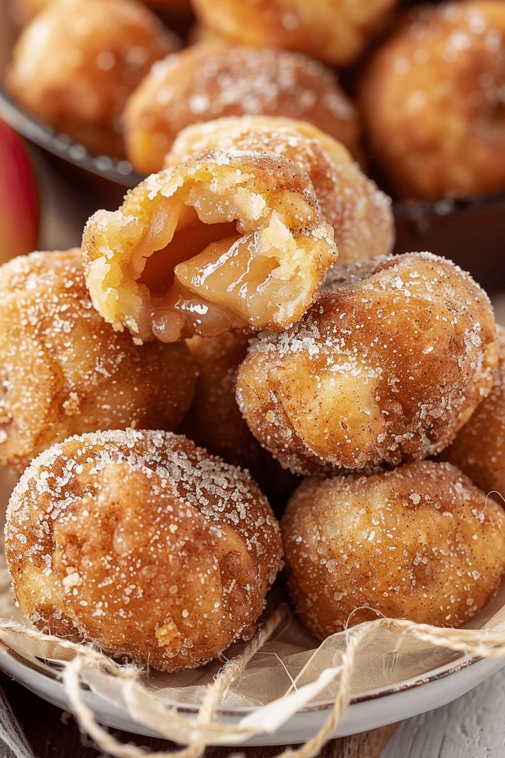 some sugared donuts are on a plate with an apple in the back ground