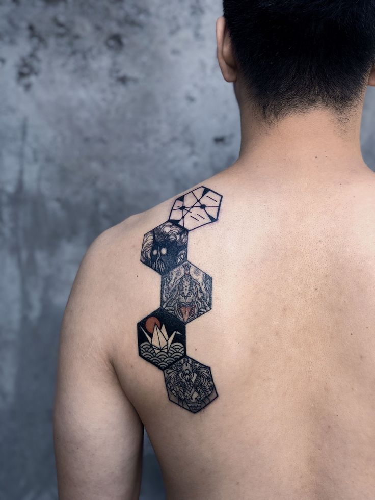 the back of a man's upper body with geometric tattoos on his shoulder and chest