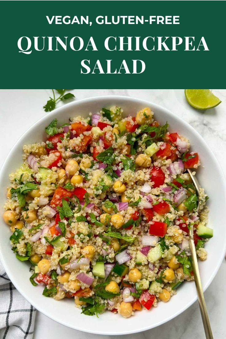 a white bowl filled with quinoa chickpea salad next to a lime wedge