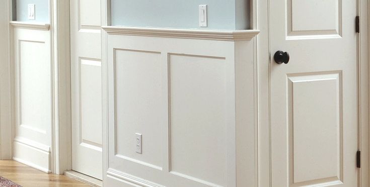 an empty room with white paneling and wood floors