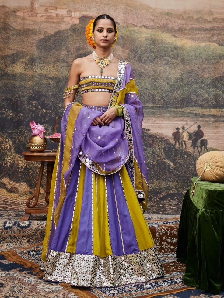 A striking ensemble, this vertical block lehenga in rich purple and vibrant yellow showcases a stunning mirror work border that adds a touch of elegance. Styled with a beautifully embellished mirror work blouse and a flowing organza dupatta, this outfit effortlessly combines contemporary flair with traditional charm, making it an ideal choice for festive celebrations. Mirror Work Border, Purple Lehenga, Mirror Work Blouse, Beach Wedding Guests, Jacket Cape, Rich Purple, Organza Dupatta, Charm Making, Indian Ethnic Wear