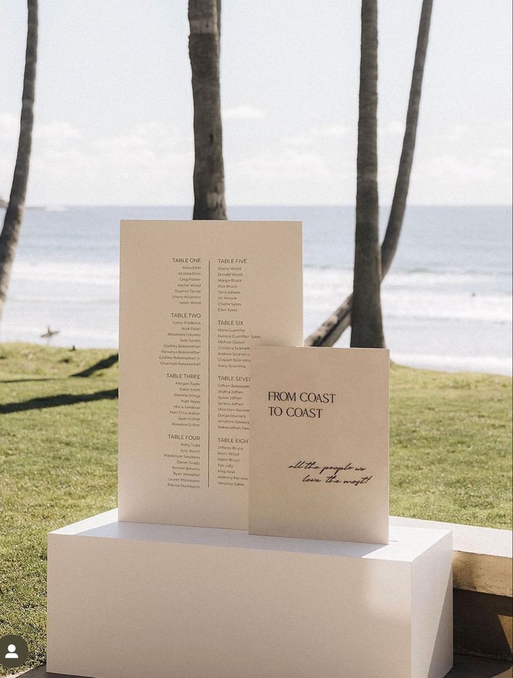 two books are stacked on top of each other in front of the ocean and palm trees