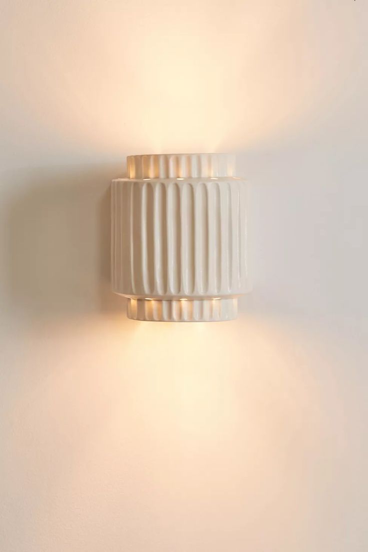 a white wall mounted light on the side of a wall