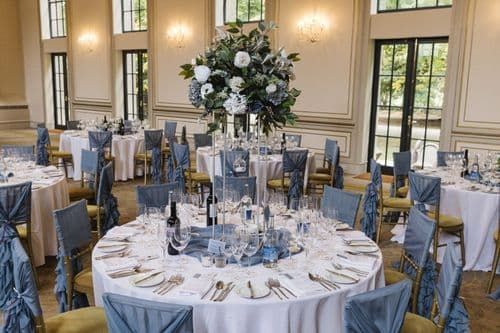 the tables are set up with blue and white linens for an elegant wedding reception