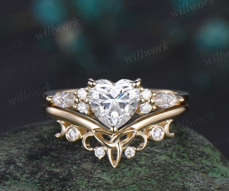 a heart shaped diamond ring on top of a rock