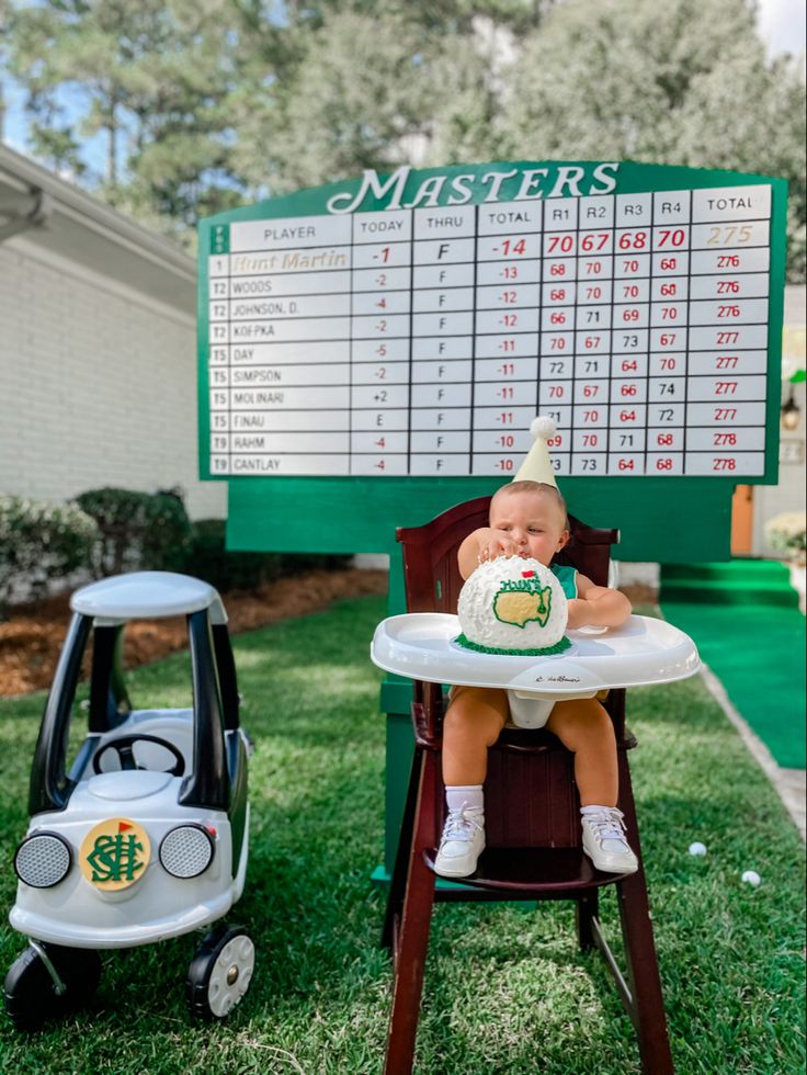 a baby sitting in a high chair next to a golf score board