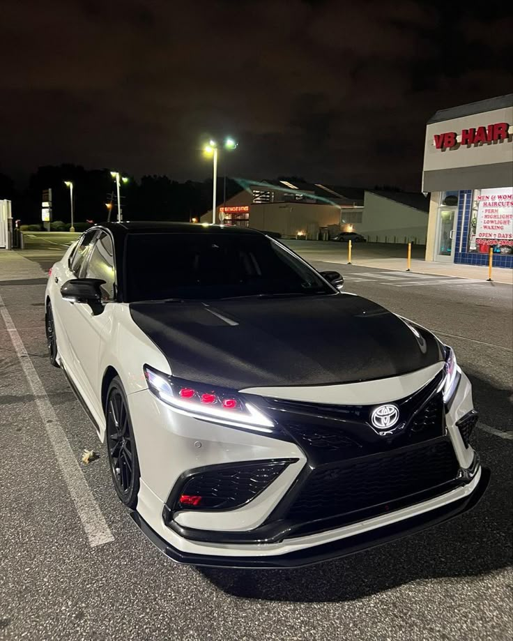 a white and black car parked in a parking lot next to a building at night