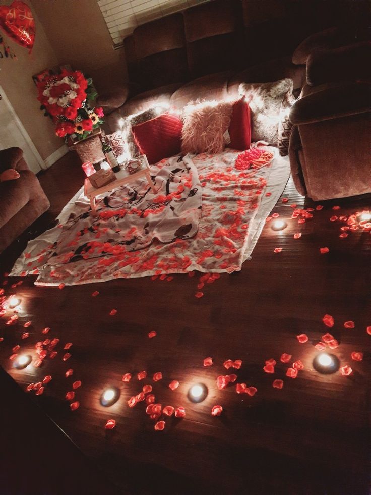 a living room filled with lots of red flowers and petals on the floor next to a couch