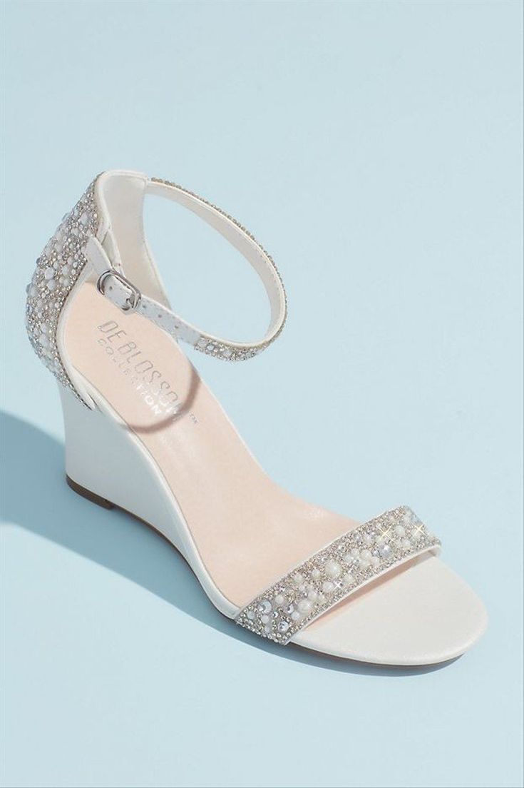 a woman's white wedged sandal with crystal embellishment on the heel