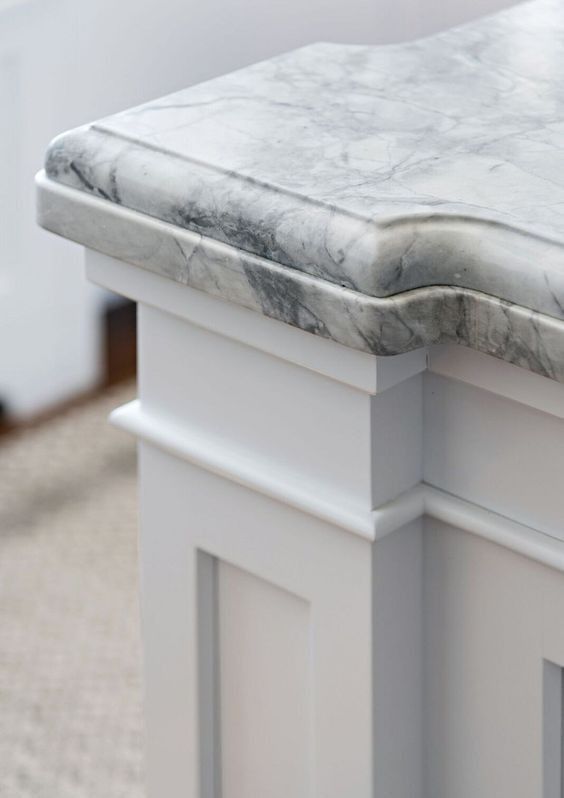 a marble top bench in a room with carpeted flooring and white walls on either side