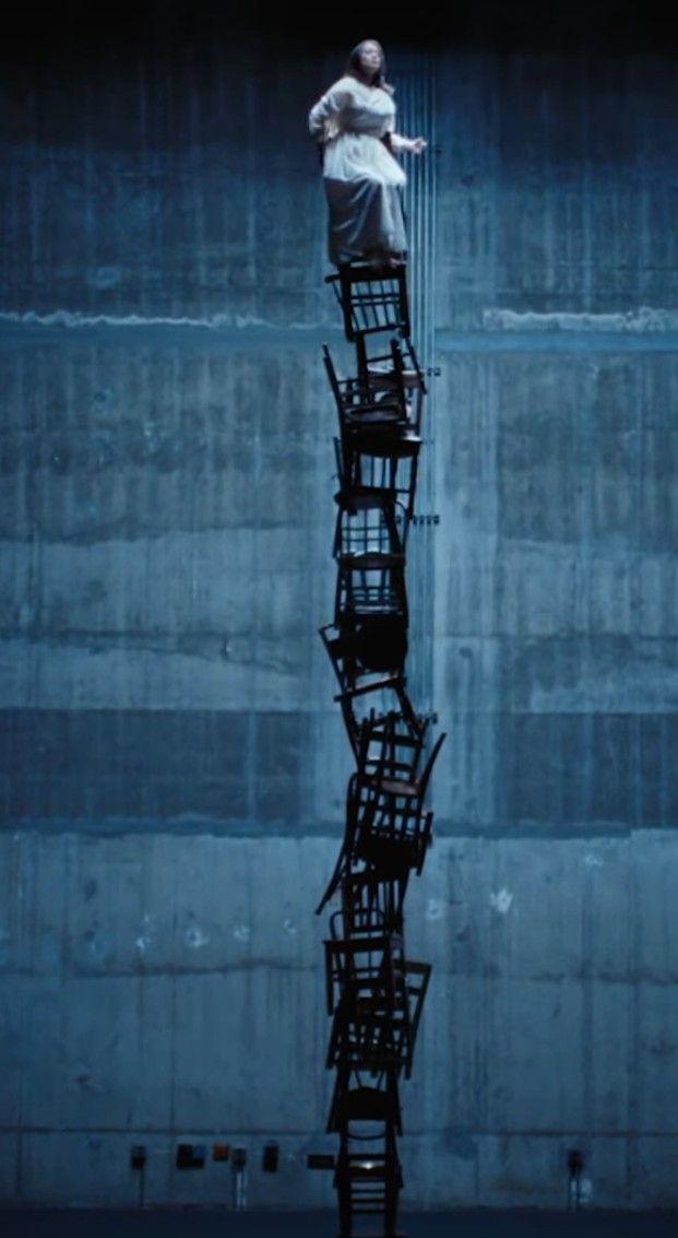 a woman standing on top of a tall metal structure in the middle of a dark room