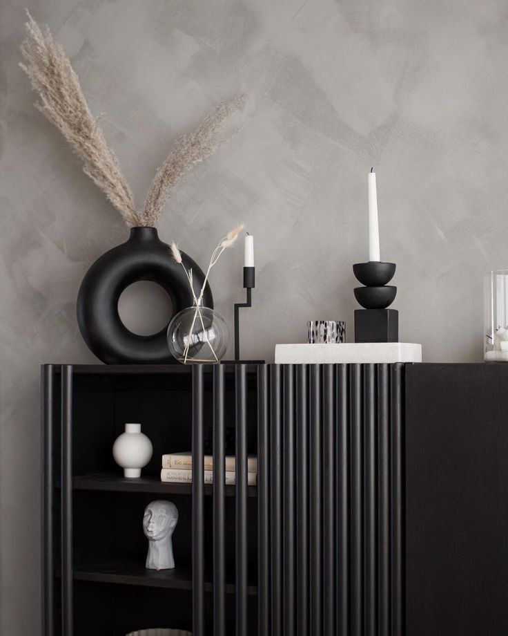 a black cabinet with candles and vases on it