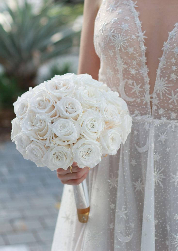 a bride holding a bouquet of white roses