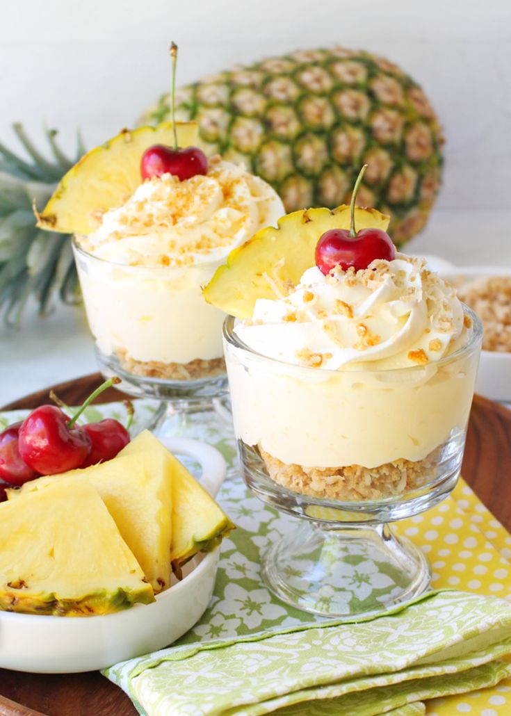 pineapple cheesecake parfait in small glass dishes with cherries on top