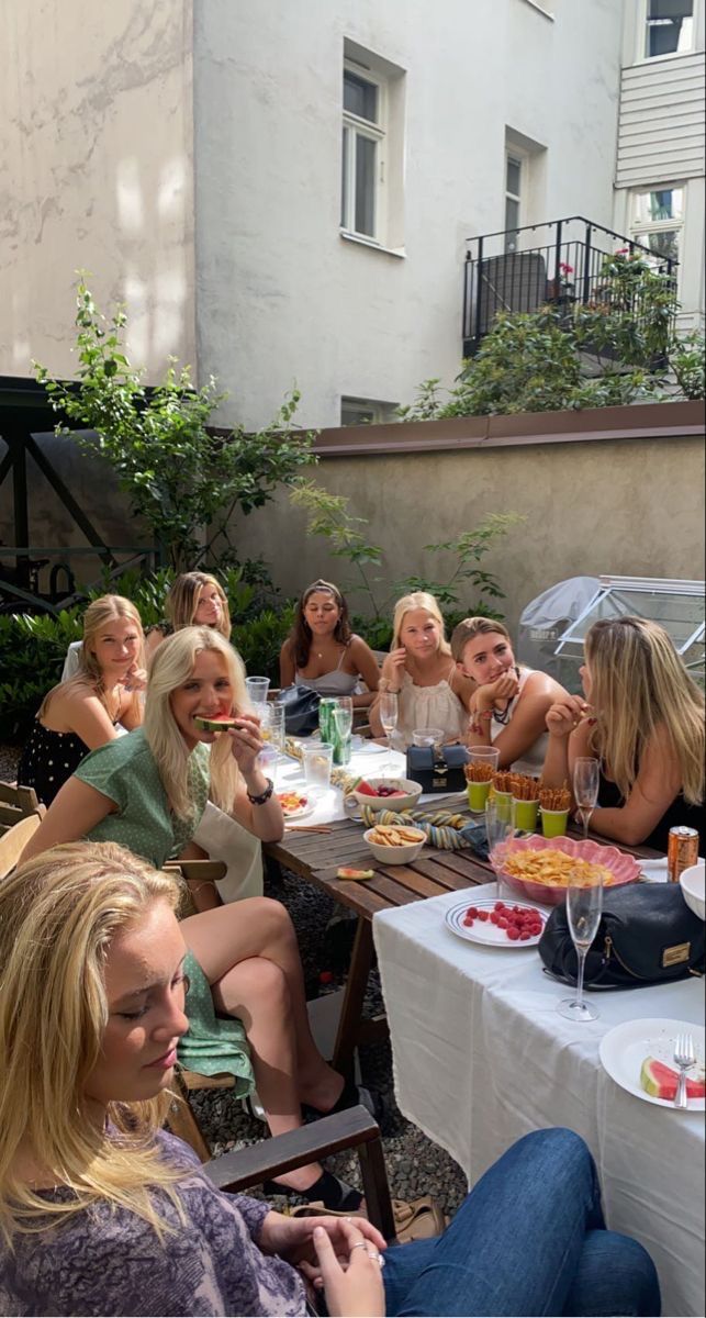 a group of women sitting around a table with food and drinks in front of them