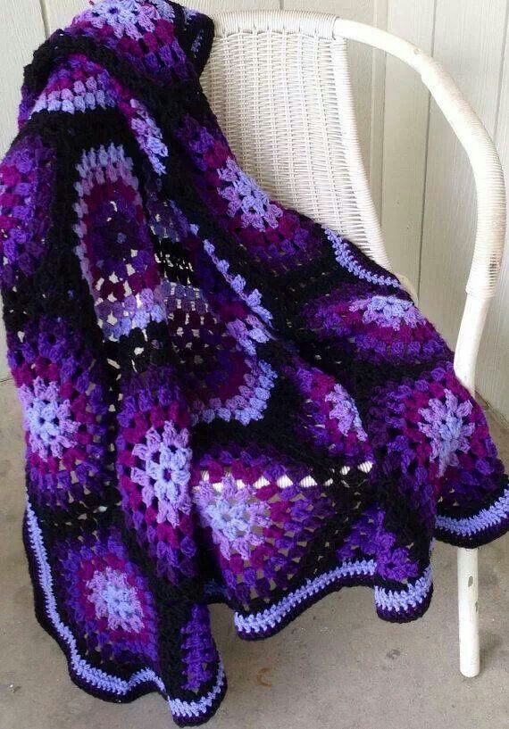 a purple and black crocheted blanket sitting on top of a white rocking chair