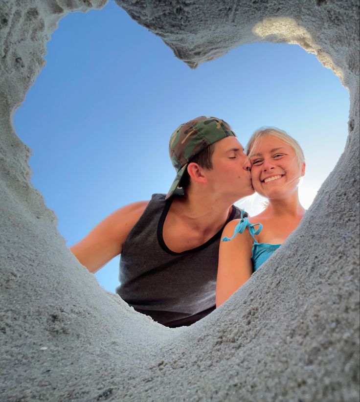 a man and woman are kissing in a heart shaped hole