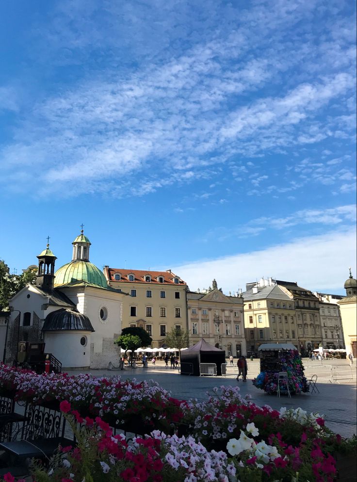 a building with a clock tower and flowers in the foreground on a sunny day