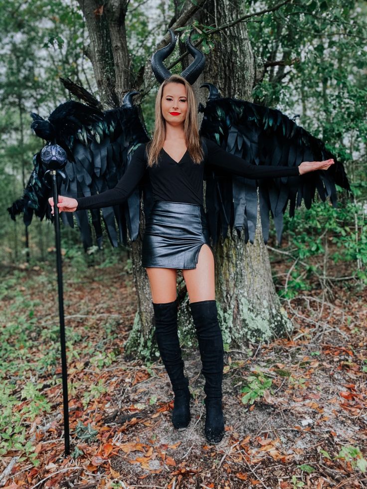 a woman dressed as an angel standing in the woods