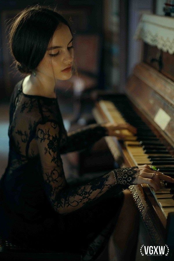 a woman sitting at a piano with her hands on the keys