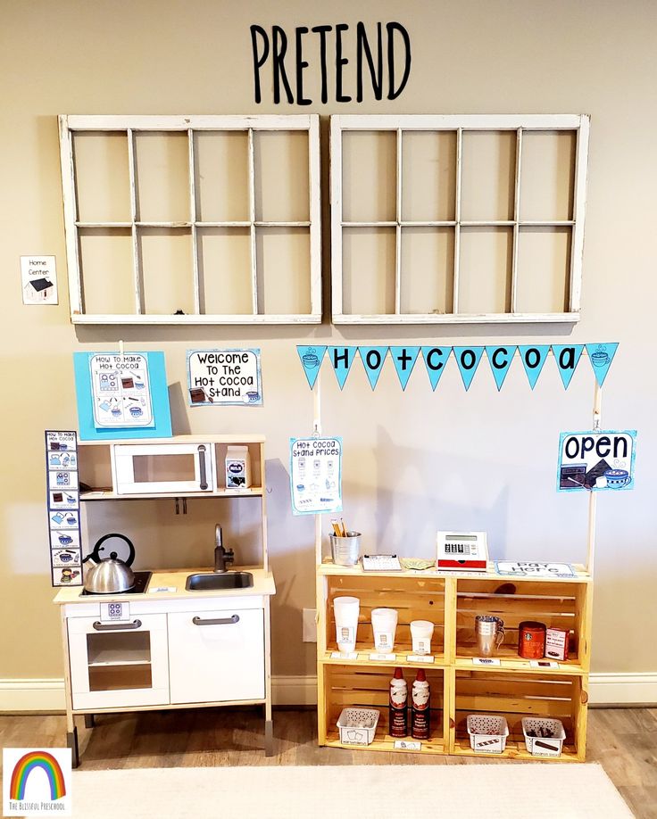 a play kitchen set up in front of a wall with words on it that say pretend