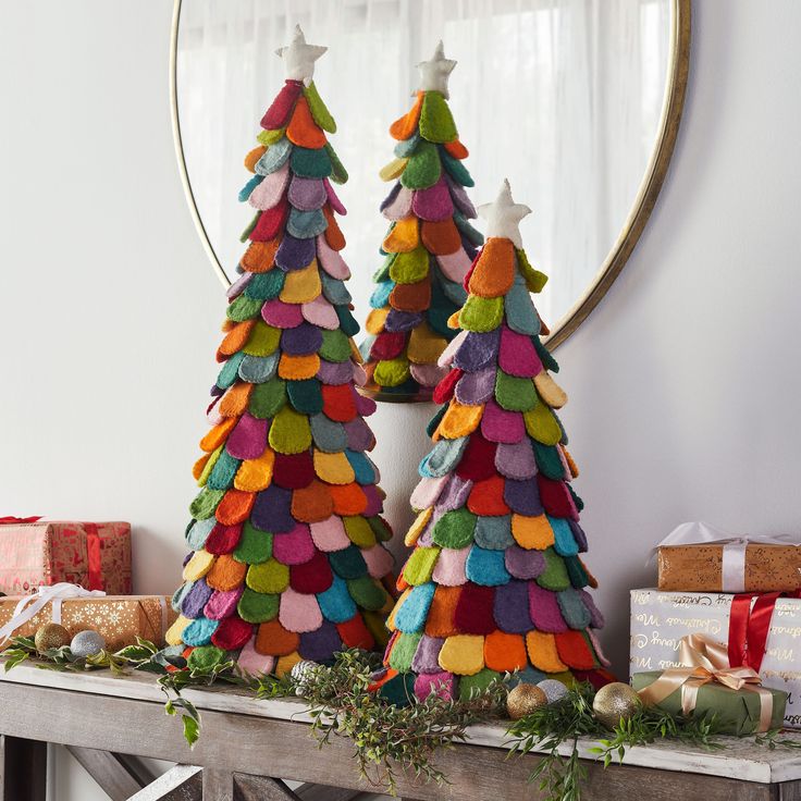 two christmas trees made out of felt sitting on top of a table next to presents