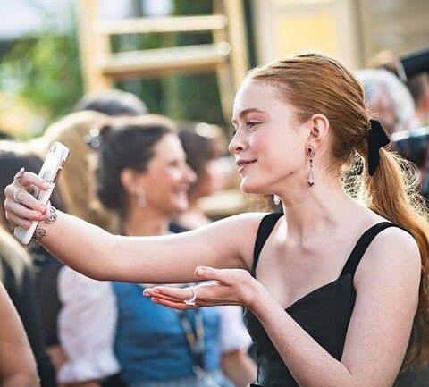 a woman is taking a selfie with her cell phone in front of other people