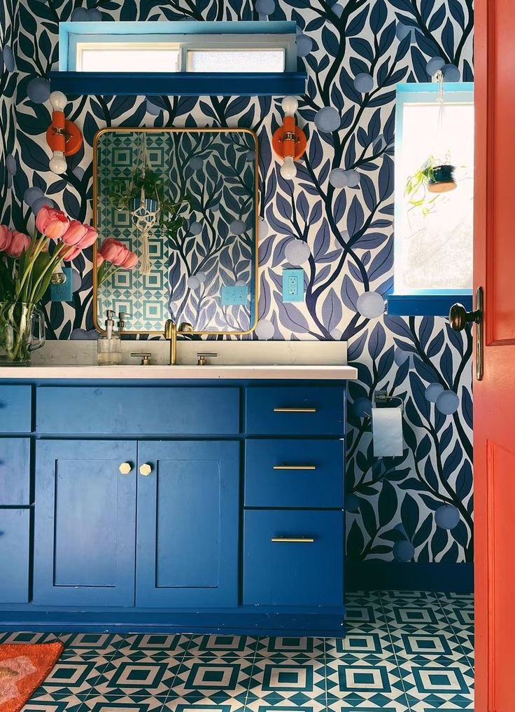 a bathroom with blue cabinets and wallpaper