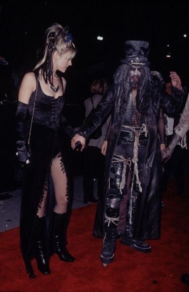 two people dressed in costumes walking on a red carpet