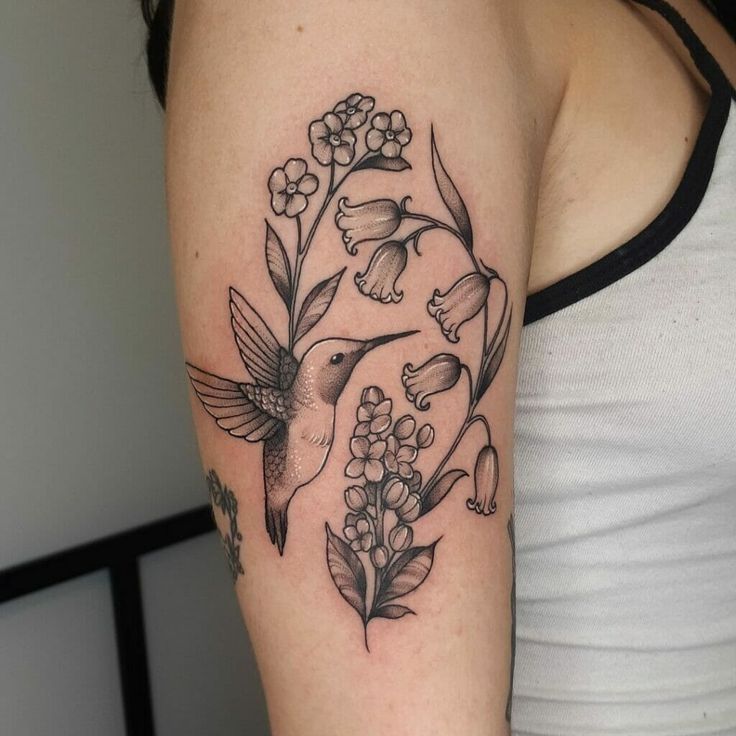 a woman with a hummingbird and flowers tattoo on her arm