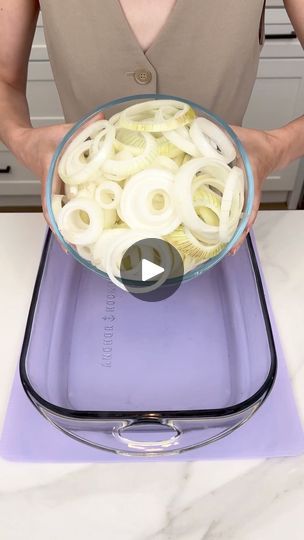 a person holding a bowl filled with onions on top of a purple mat in the kitchen