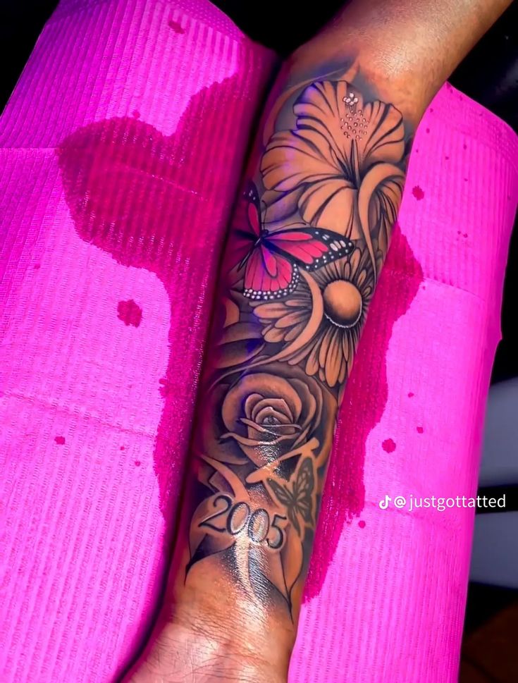 a woman's arm with flowers and butterflies on it