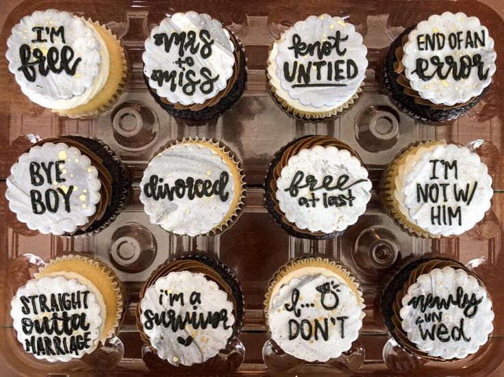 twelve cupcakes with white frosting and black writing on them