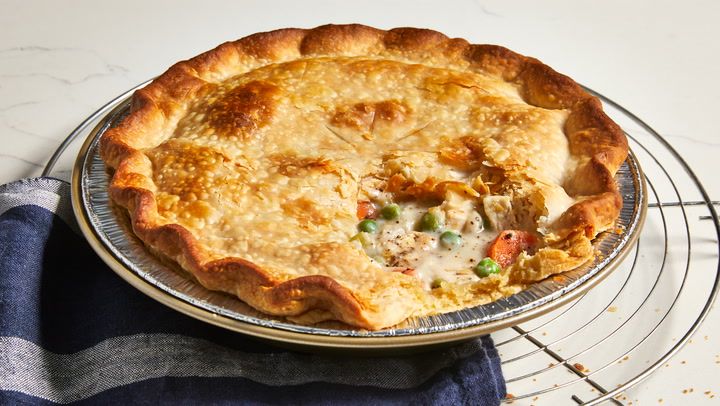 a chicken pot pie sitting on top of a metal rack next to a blue and white towel