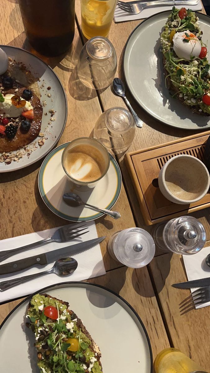 a wooden table topped with plates of food and drinks