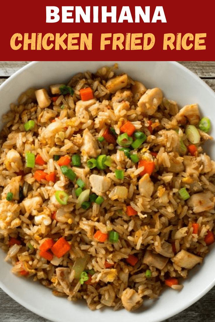 a white bowl filled with fried rice and veggies on top of a wooden table