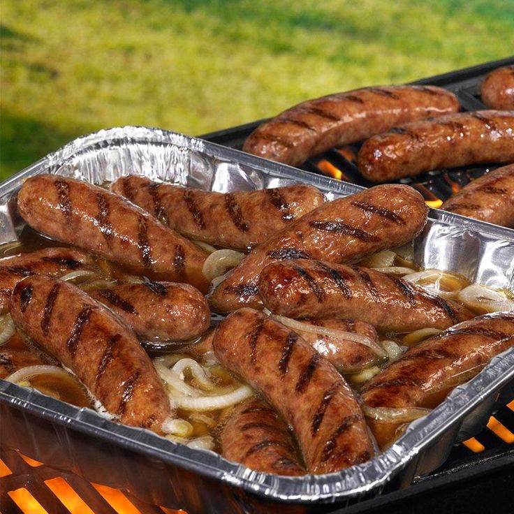 sausages and onions cooking on an outdoor grill