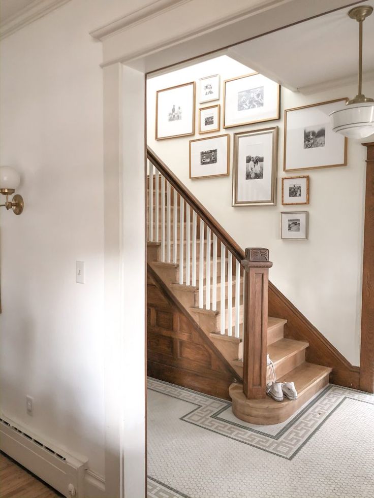 an entryway with stairs and framed pictures on the wall above it in a home