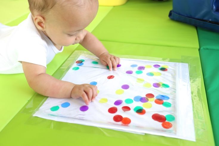 a baby is playing with colored dots on a piece of paper in the middle of a play area